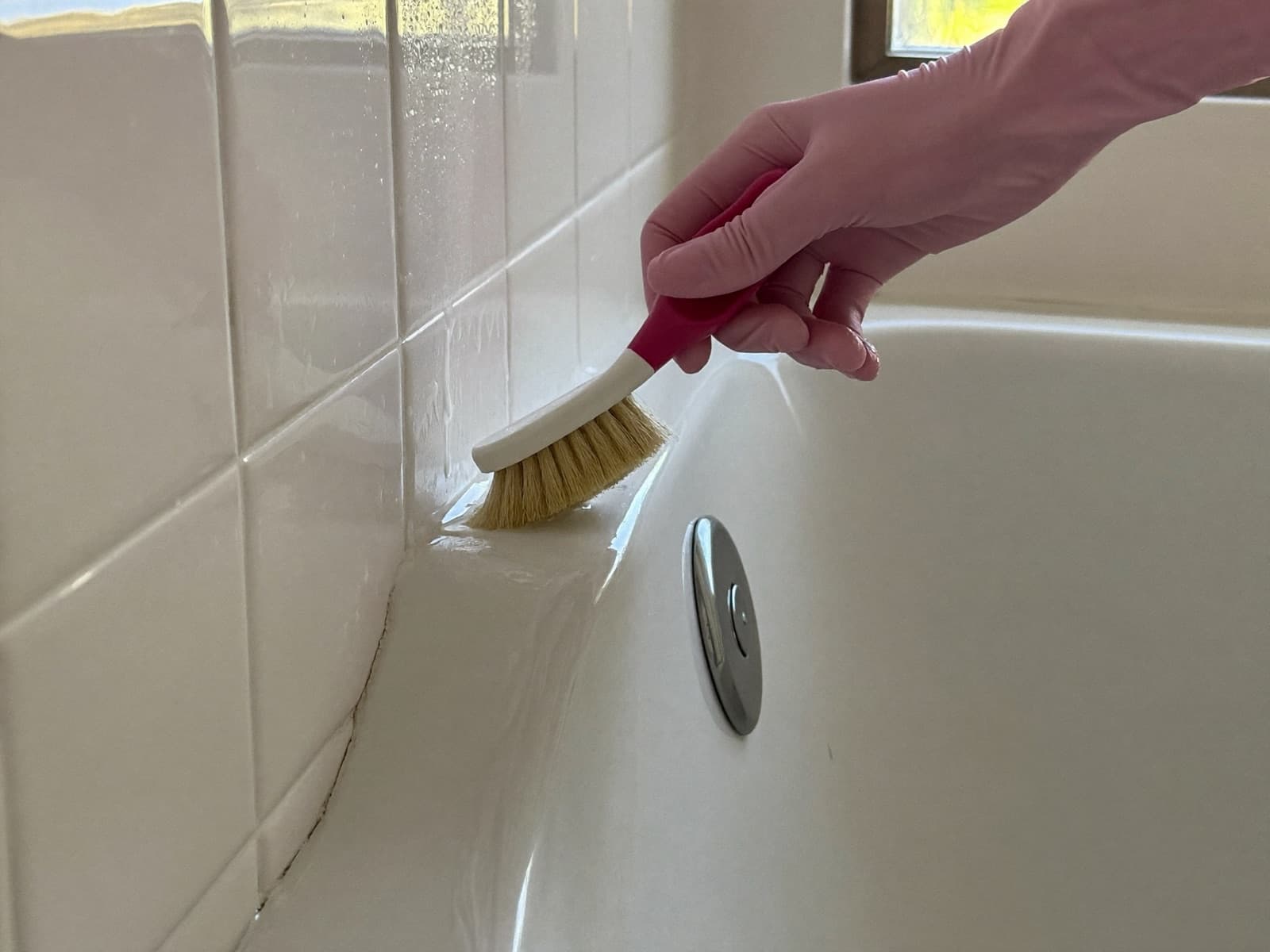 Scrubbing bathroom tile grout and a baseboard with a small brush